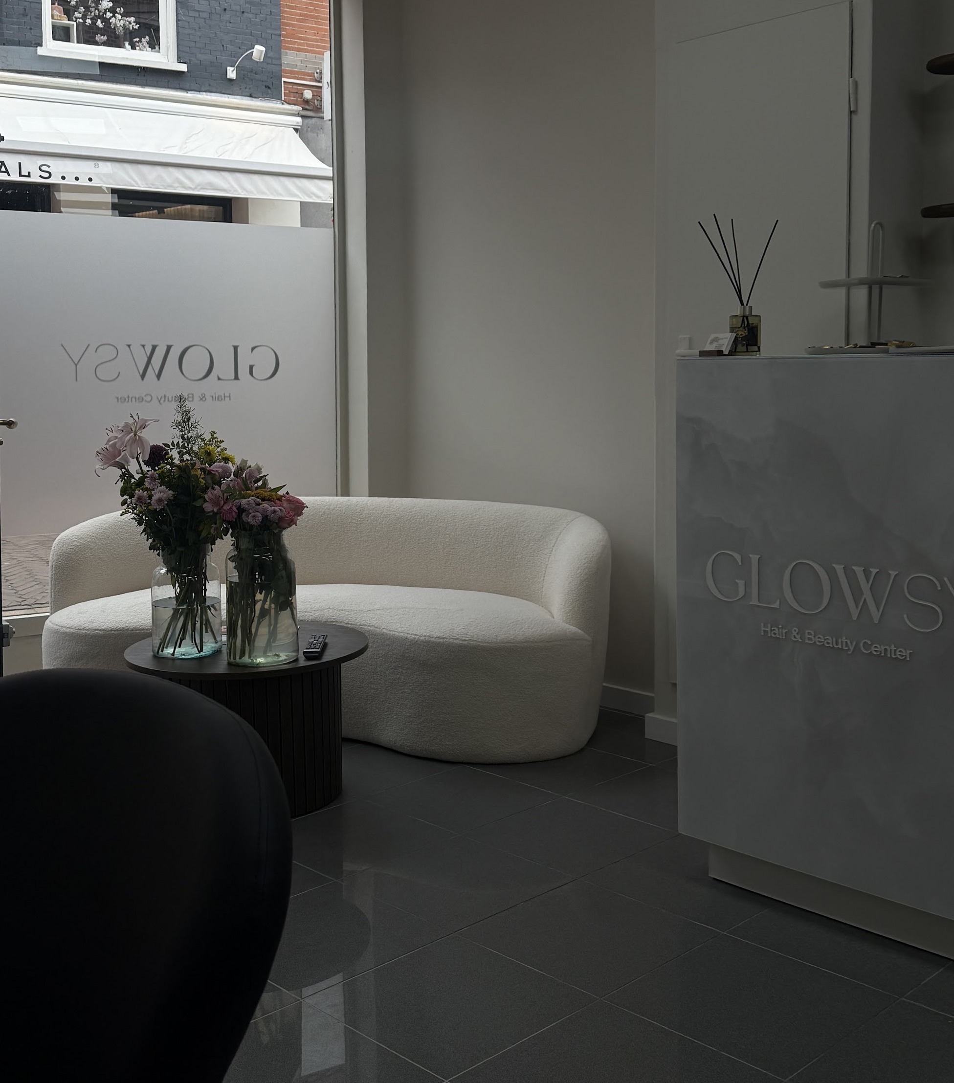 De ontvangst van Glowsy Center met een gebogen lichte bank en bloemen